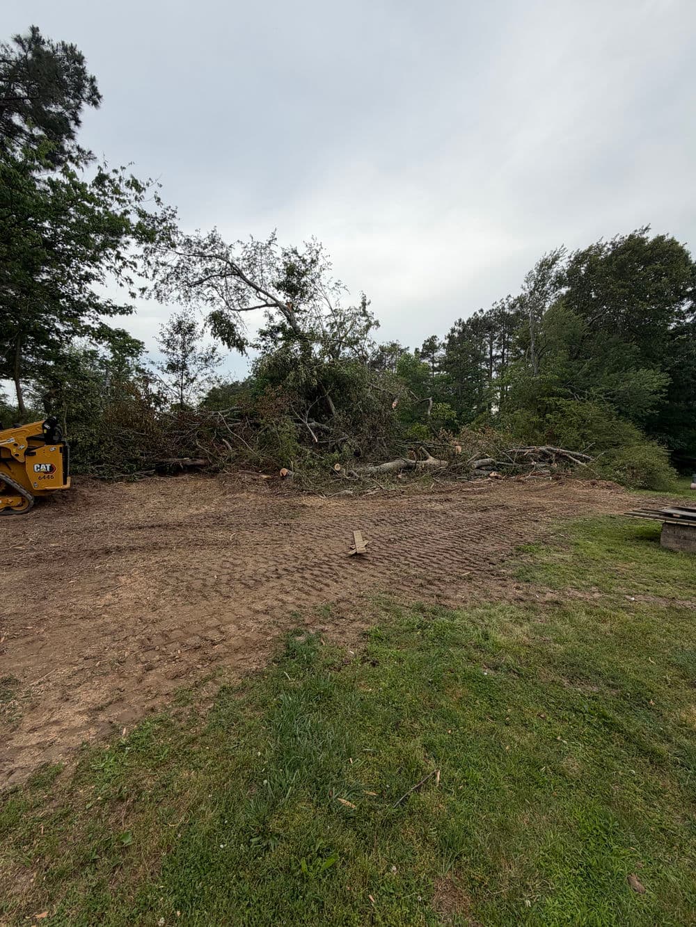 Cleared land with tree debris and equipment for landscaping or construction.